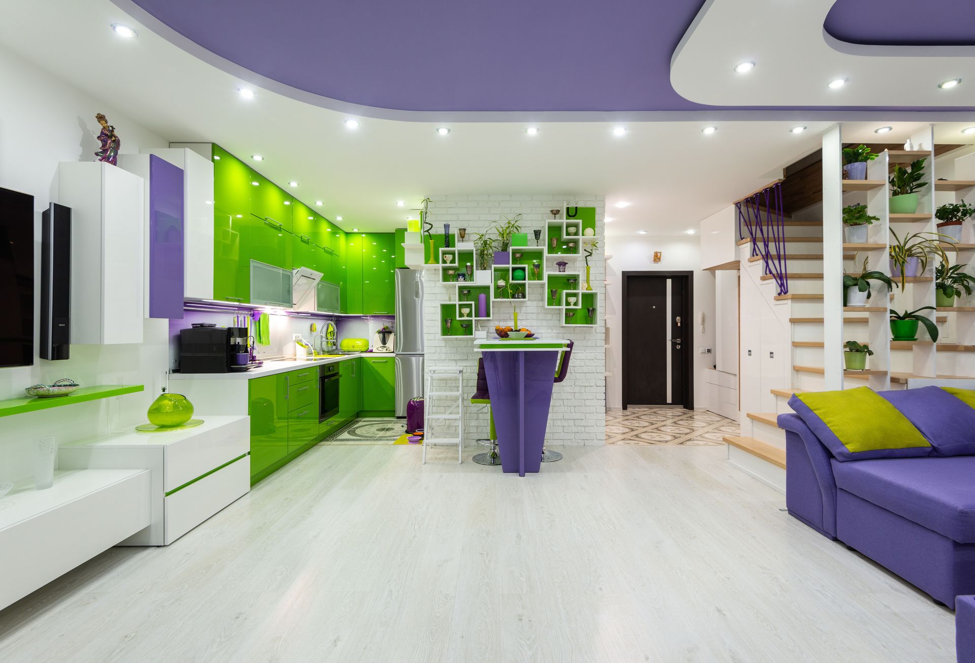 Creative interior of spacious studio apartment with bright green and purple furniture in living room and kitchen and modern appliances